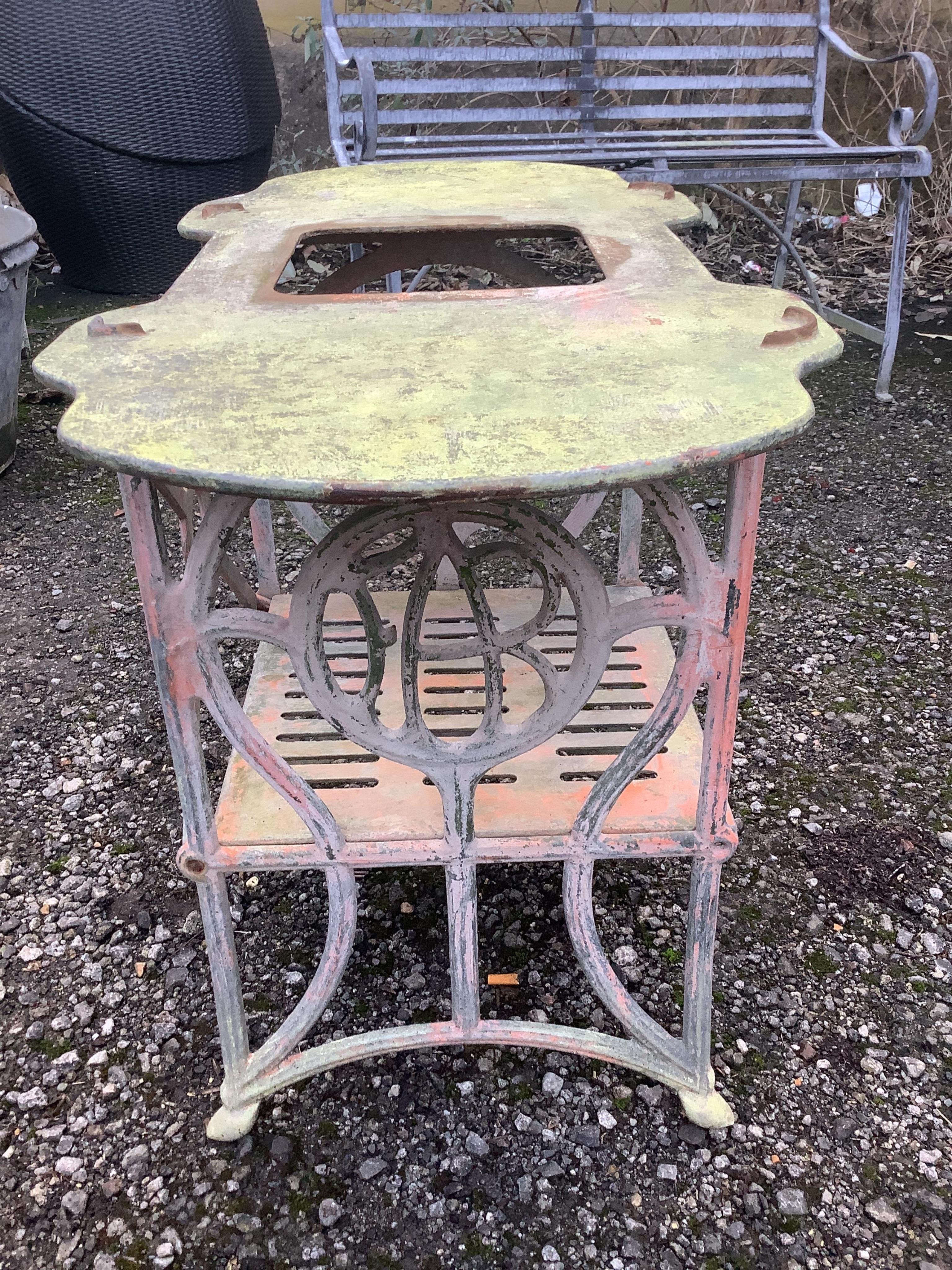 A small white painted cast metal two tier table, with a shaped top, width 78cm, height 59cm. Condition - fair